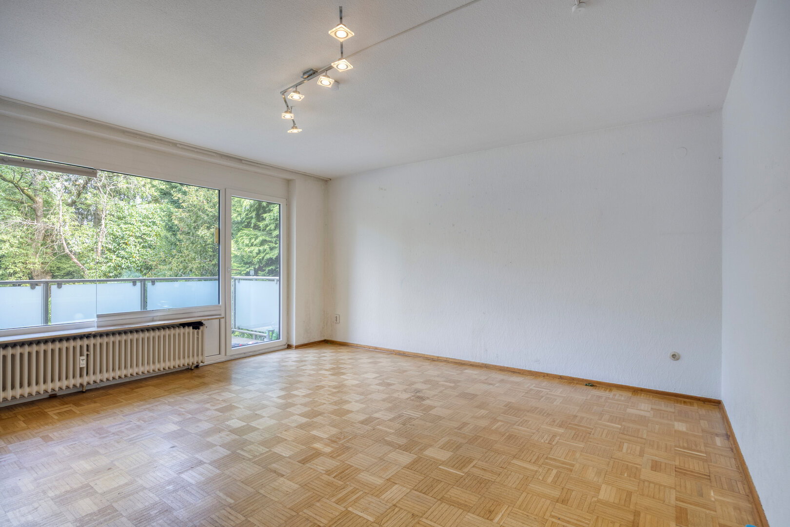 Eigentumswohnung Ratingen – Wohnzimmer mit Parkettboden und großer Fensterfront